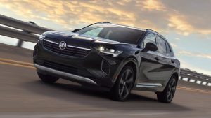 Black 2021 Buick Envision driving on a cliff road with the sunset in the background.