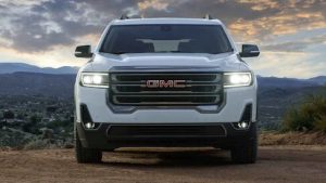 Front-facing white 2021 GMC Acadia parked in an open field.