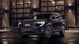 Black 2021 GMC Terrain parked in front of a building at night.